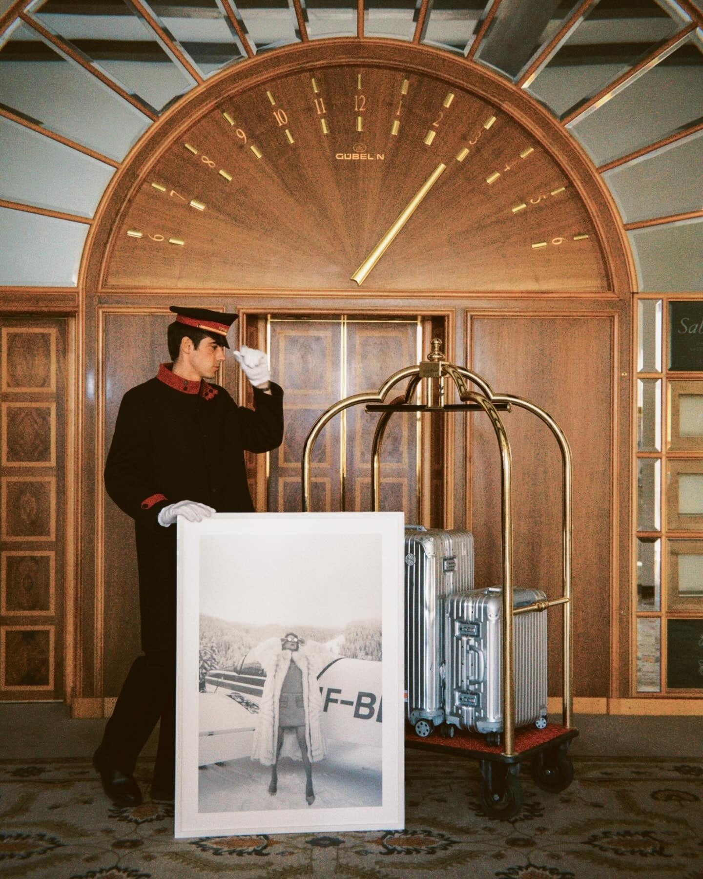 St. Moritz hotel entrance with a porter, framed photograph and luggage trolley — owner-selected exhibition image
